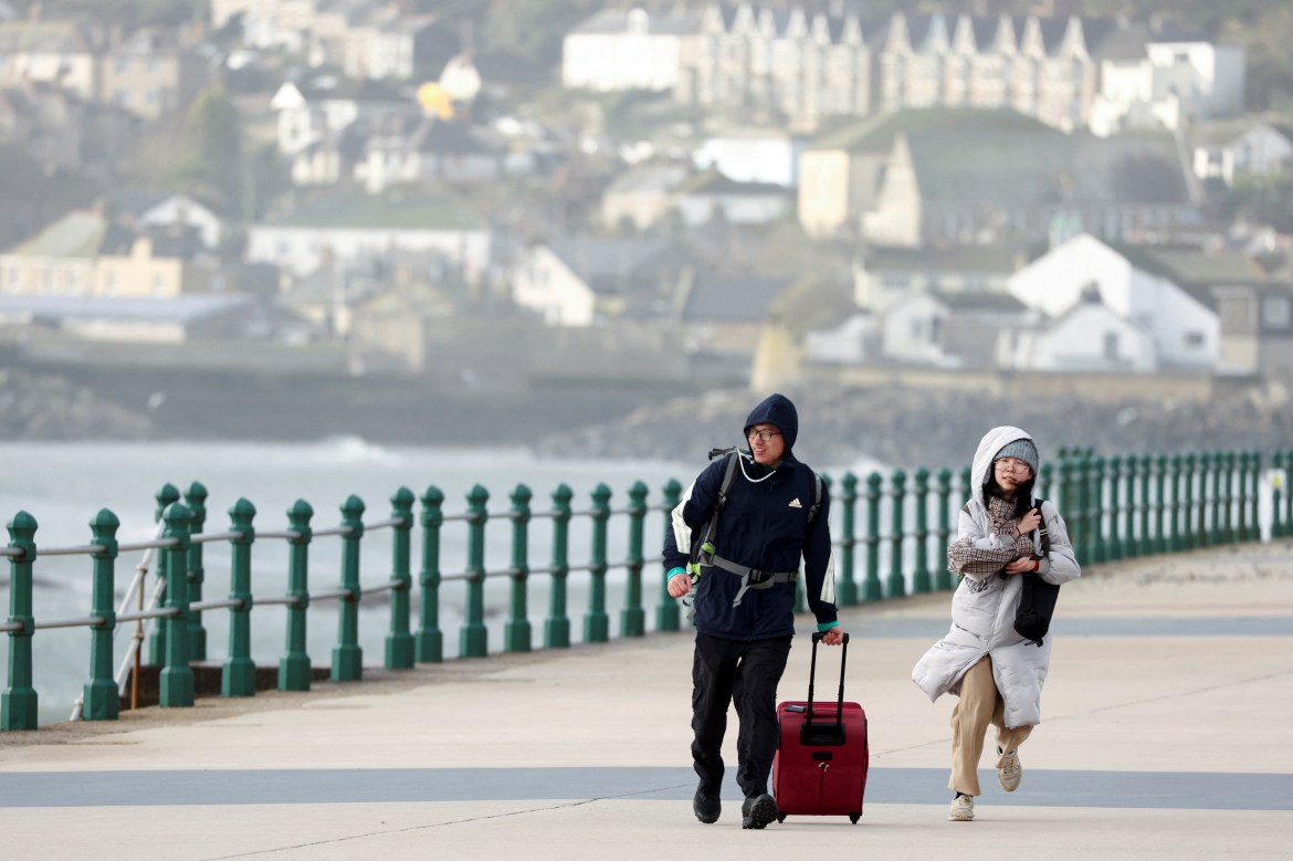 People walk along Penzance Promenade during Storm Eunice, in Penzance, Cornwall, Britain, February 18, 2022. REUTERS/Tom Nicholson