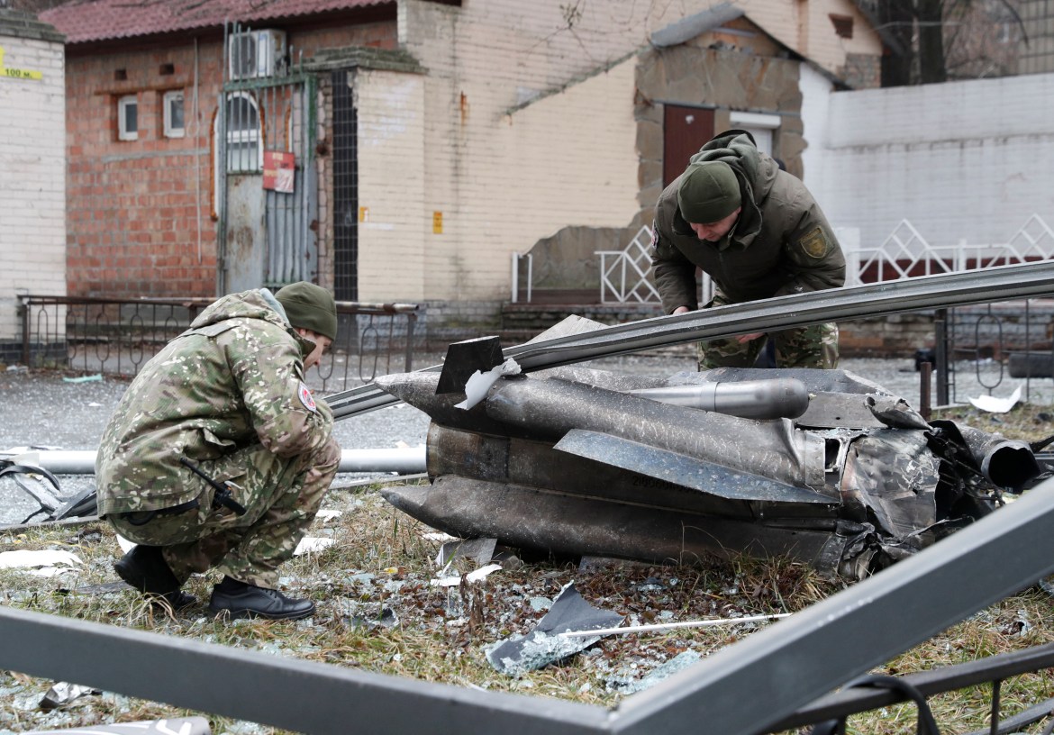 Police officers inspect the remains of a missile that fell in the street,