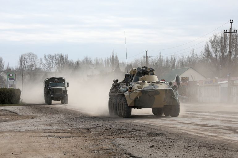 Military vehicles drive along a street