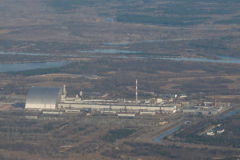 An aerial view from a plane shows a New Safe Confinement (NSC) structure over the old sarcophagus covering the damaged fourth reactor at the Chernobyl Nuclear Power Plant during a tour to the Chernobyl