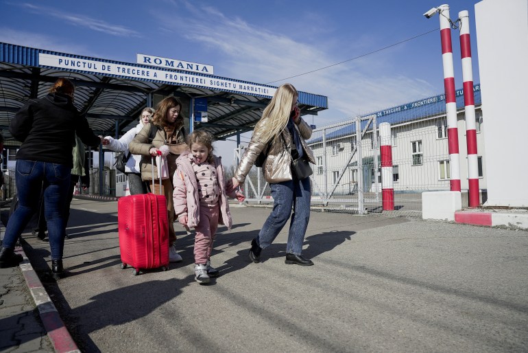 A woman holds the arm of her child as they arrive from Ukraine to Romania
