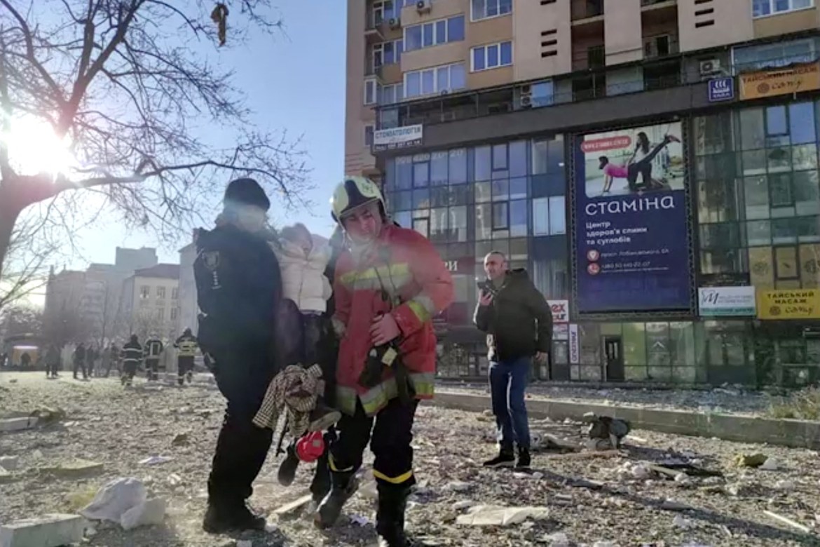service workers carrying a person at the site of a damaged multi-storey residential building