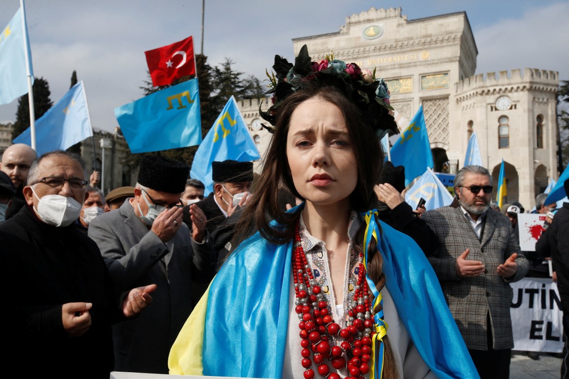 A woman wears a Ukrainian flag as people pray during an anti-war protest, after Russia launched a massive military operation against Ukraine, in Istanbul