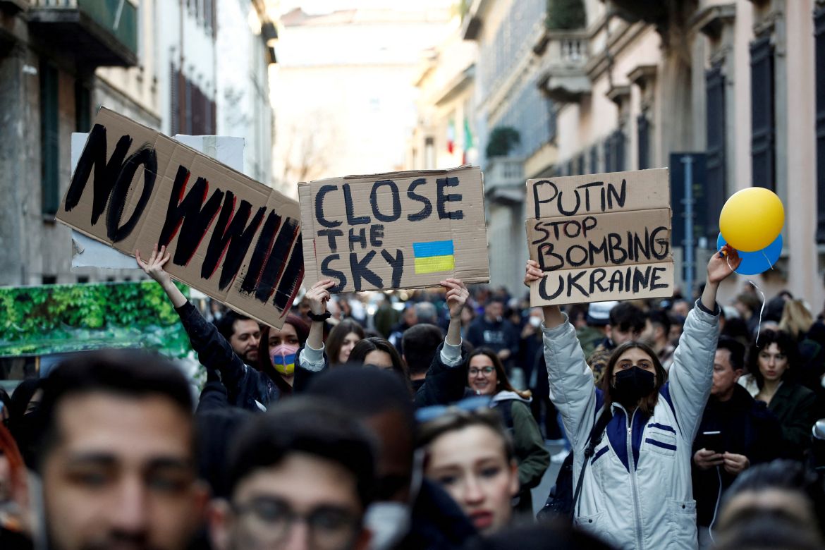 People hold up placards at an anti-war protest during the Fashion Week, after Russia launched a massive military operation against Ukraine, in Milan