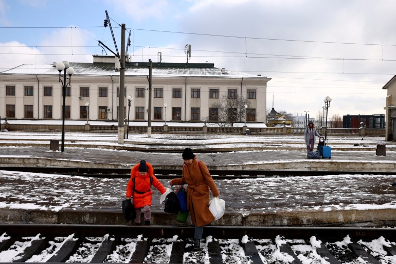 Las personas que huyen de la invasión rusa de Ucrania, cruzan las vías del tren hacia un tren con destino a Polonia, en la estación de tren de Lviv, Ucrania Febrero 