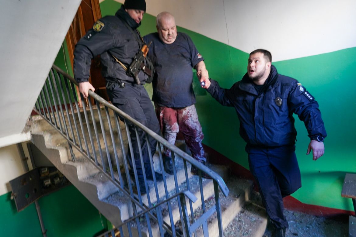 Ukrainian security forces accompany a wounded man after an airstrike hit an apartment complex in Chuhuiv, Kharkiv Oblast, Ukraine