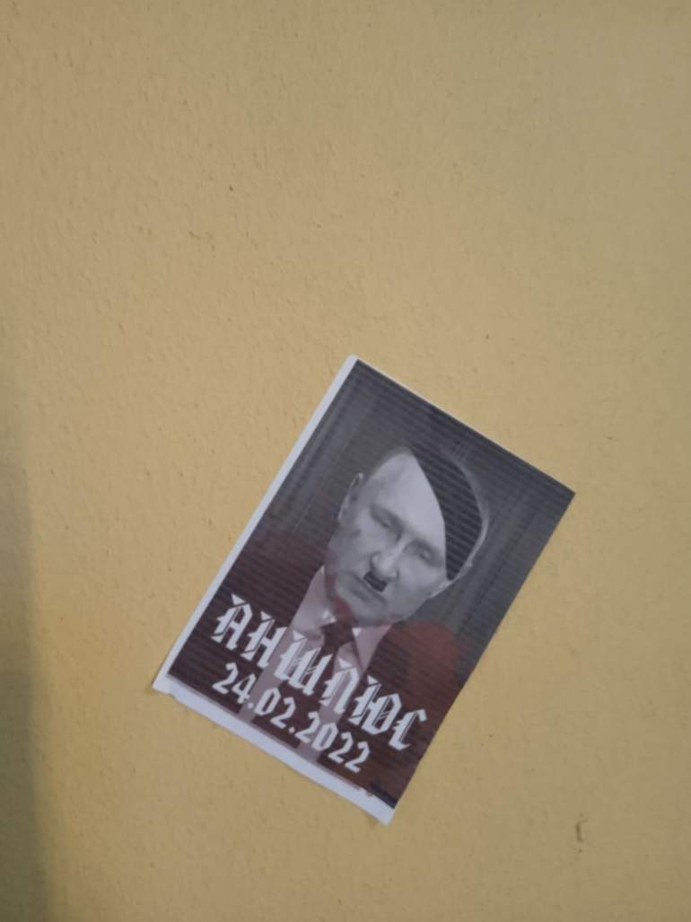 El cartel de un manifestante muestra a Putin como Hitler con la palabra Anschluss, refiriéndose a la anexión de Austria a Alemania antes de la Segunda Guerra Mundial. [Niko Vorobyov/Al Jazeera]