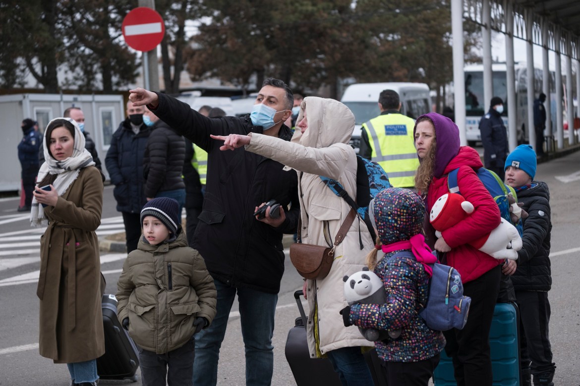 A representative of the Romanian gendarmerie guides newly arrived refugees towards the volunteers providing food and transportation.
