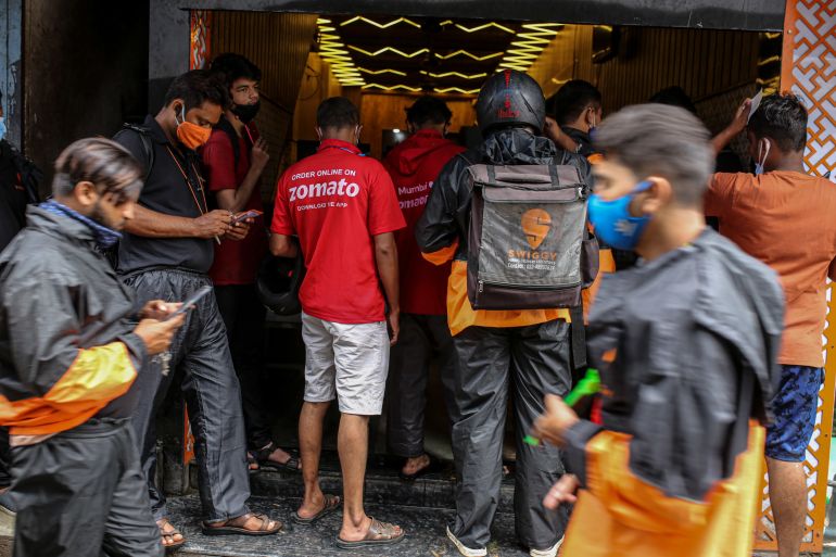 Delivery riders for Zomato and Swiggy, wait to collect orders outside a restaurant in Mumbai, India