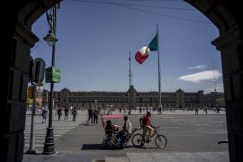 A bicycle taxi drives customers past Constitution Square, known as Zocalo, in Mexico City, Mexico