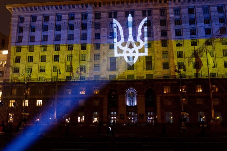The Ukrainian coat of arms and national flag is projected onto a building in Kyiv, Ukraine