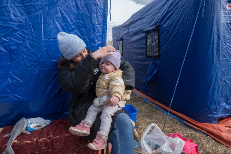 A Ukrainian mother takes a break to feed her baby at the temporary shelter tents near the Siret border crossing.