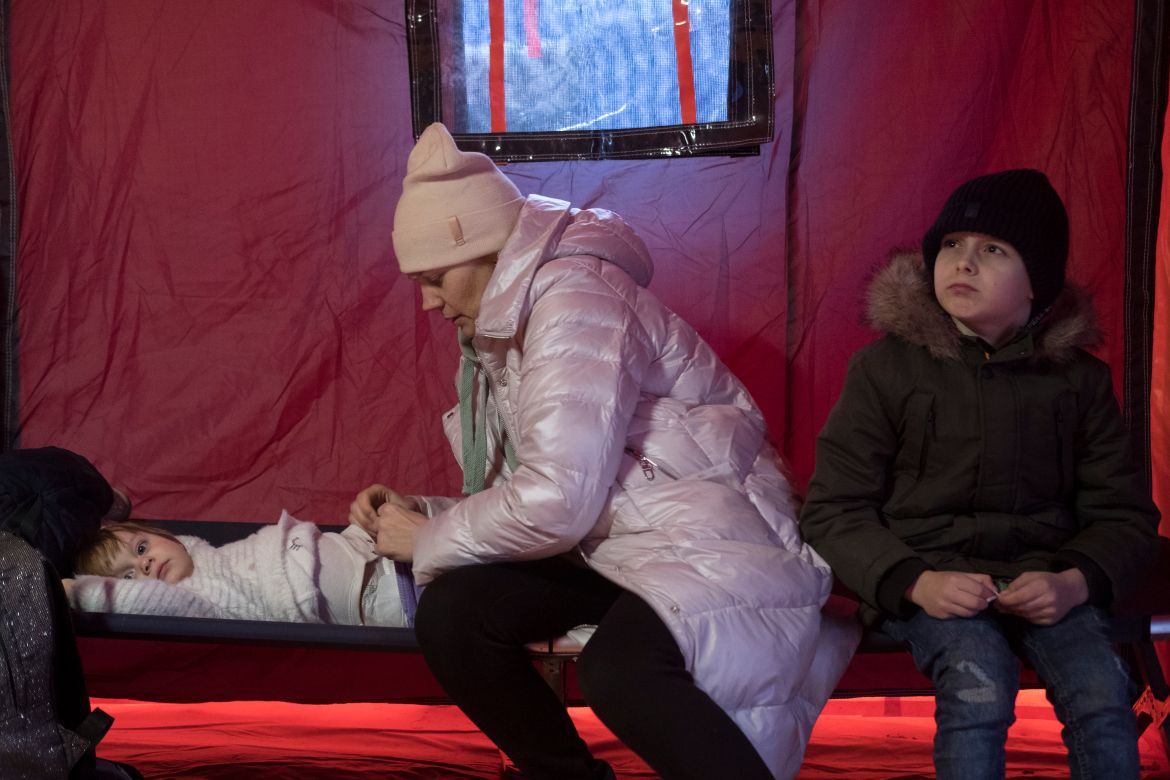 A Ukrainian mother tends to her children after the long journey in a temporary shelter tent nearby the Siret border crossing.