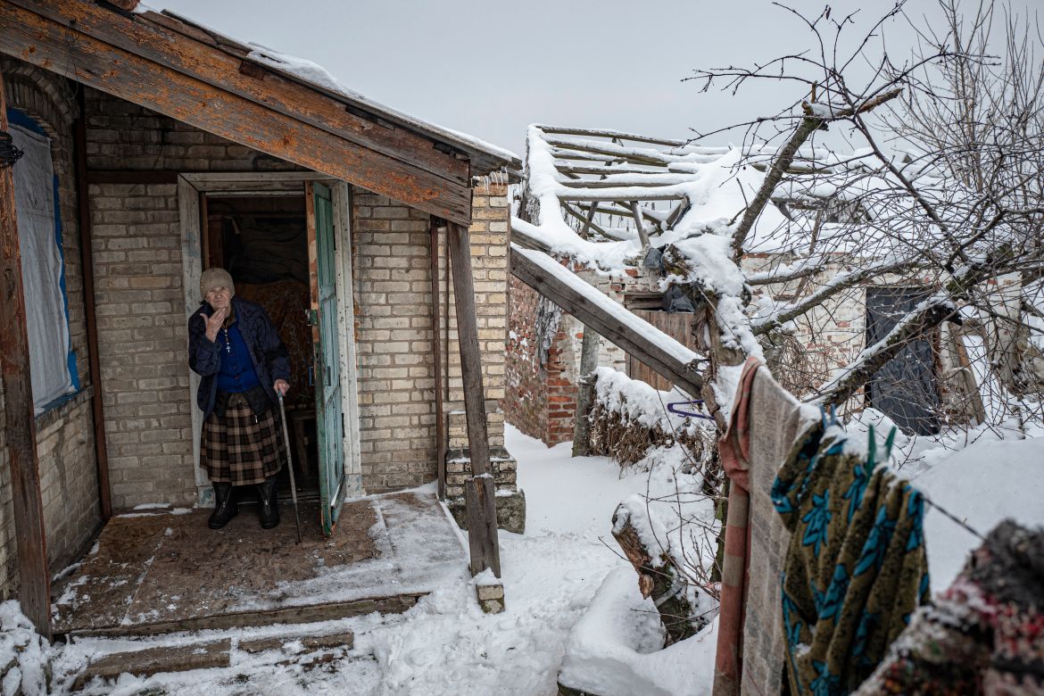 Lydia, 85, opens the door of her dilapidated house surrounded by soldiers and landmines.