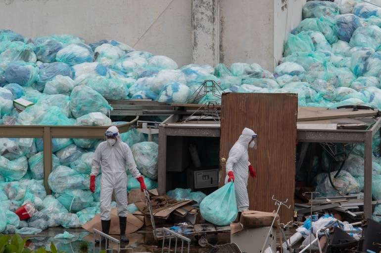 medical workers using protective equipment dispose of trash bags containing hazardous biological waste into a large pile outside the Hospital del Instituto Mexicano del Seguro Social, which treats patients with COVID-19 in Veracruz, Mexico.