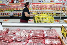a shopper wears a mask as she walks through the meat products at a grocery store in Dallas, Texas USA