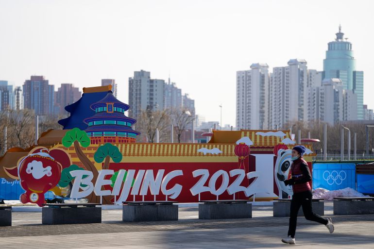 A woman jogs past an installation near the Beijing Olympic Park at the 2022 Winter Olympics, Tuesday, Jan. 25, 2022, in Beijing. (AP Photo/Jae C. Hong)