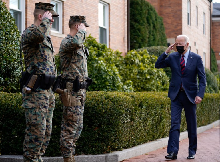 President Joe Biden returns a salute as he walks by the Marine Barracks in Washington, DC