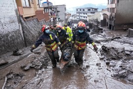 Image of Rescue workers carrying away the body of a victim after flash flooding triggered by rain filled up nearby streams that burst their containment mechanisms, collapsing a hillside and bringing waves of mud over homes in La Gasca area of Quito, Ecuador