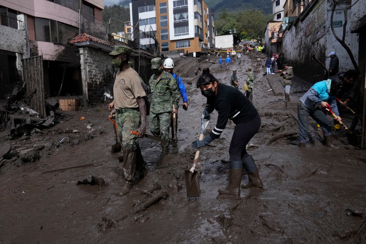 Residents and soldiers work to clear mud from streets after a rain-weakened hillside collapsed and brought waves of mud over La Gasca area of Quito, Ecuador, Tuesday, Feb. 1, 2022.