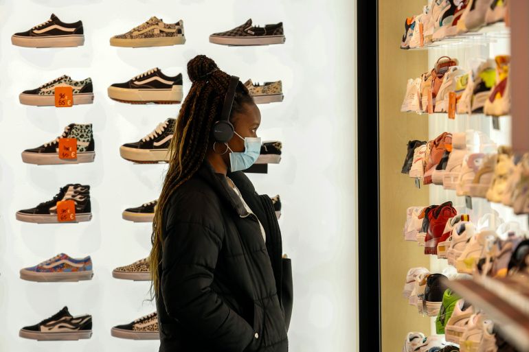 A woman wears a protective mask as she looks at shoes in Rue Neuve in Brussels, Belgium