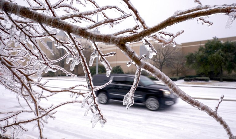 Ice coats trees and the road as an SUV drives in Richardson, Texas.