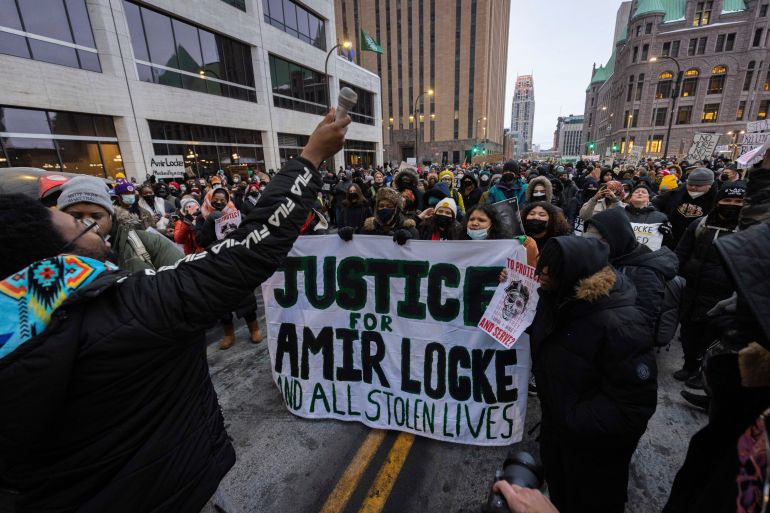 People march at a rally for Amir Locke holding a sign calling for justice