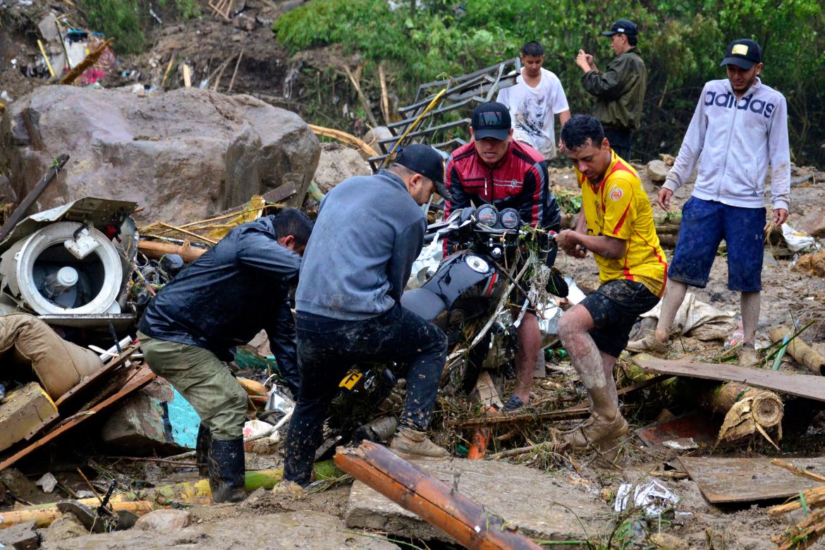 Residents lift a motorcycle from the debris