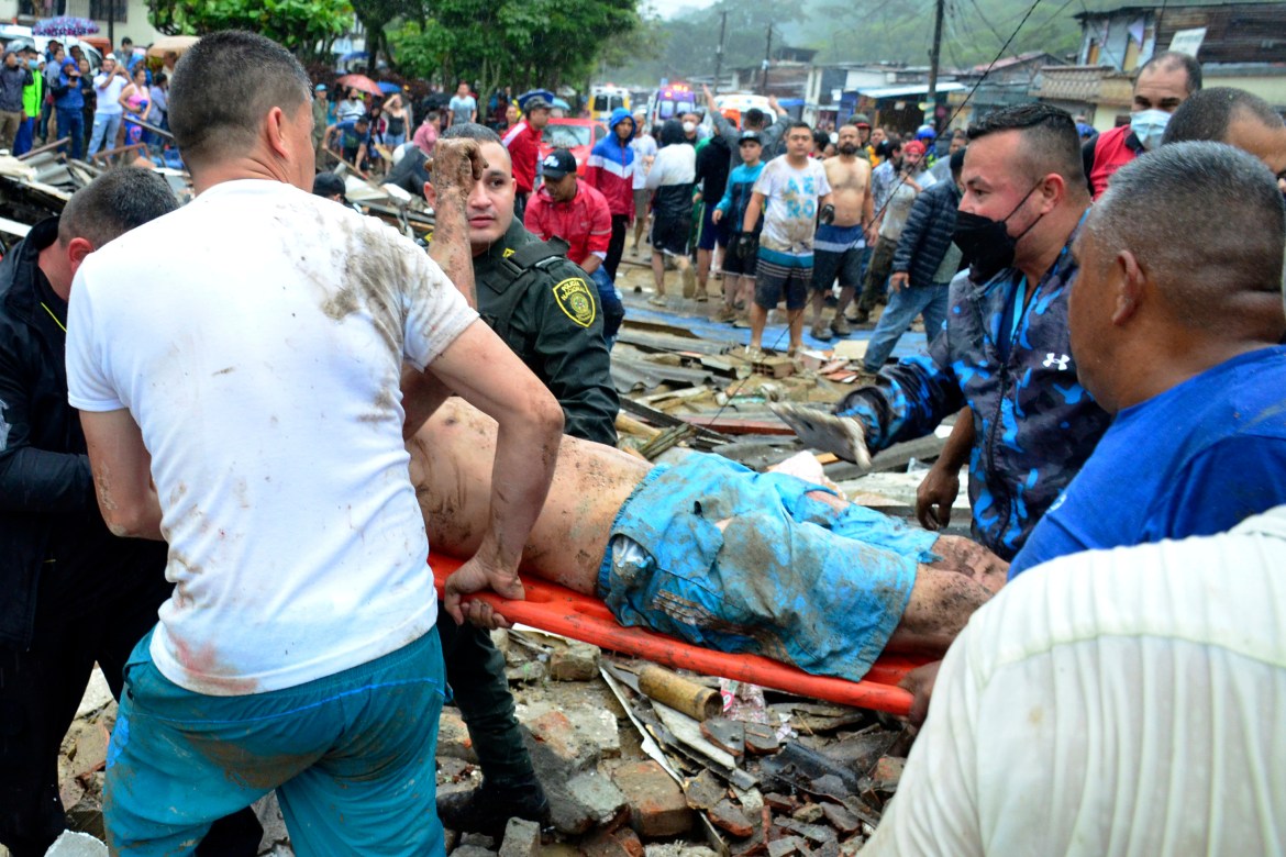 Police and rescue workers evacuate a survivor from the site of a rain-weakened hillside that collapsed over homes in Pereira