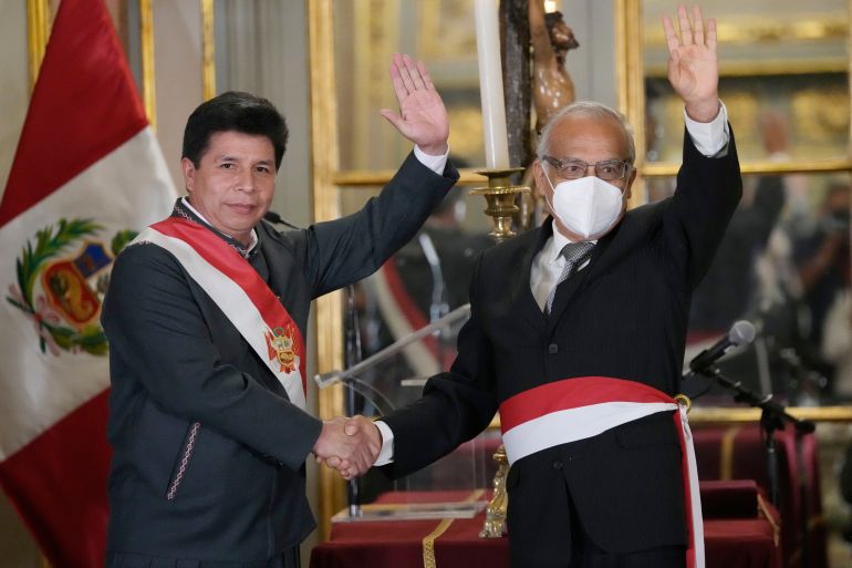 Peru's President Pedro Castillo, left, waves alongside his new Cabinet Chief Anibal Torres, during the swearing-in of Castillos´s new Cabinet, at the government palace in Lima, Peru, Tuesday, Feb. 8, 2022