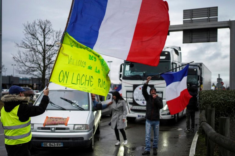 A protester waves a French flag at a convoy made of vehicles, from trucks to motorcycles and camper vans, in Lyon.