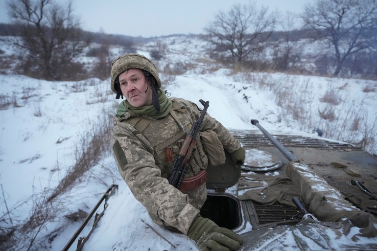 A Ukrainian serviceman looks back from atop an armored personnel carrier driving near a front line position in the Luhansk area