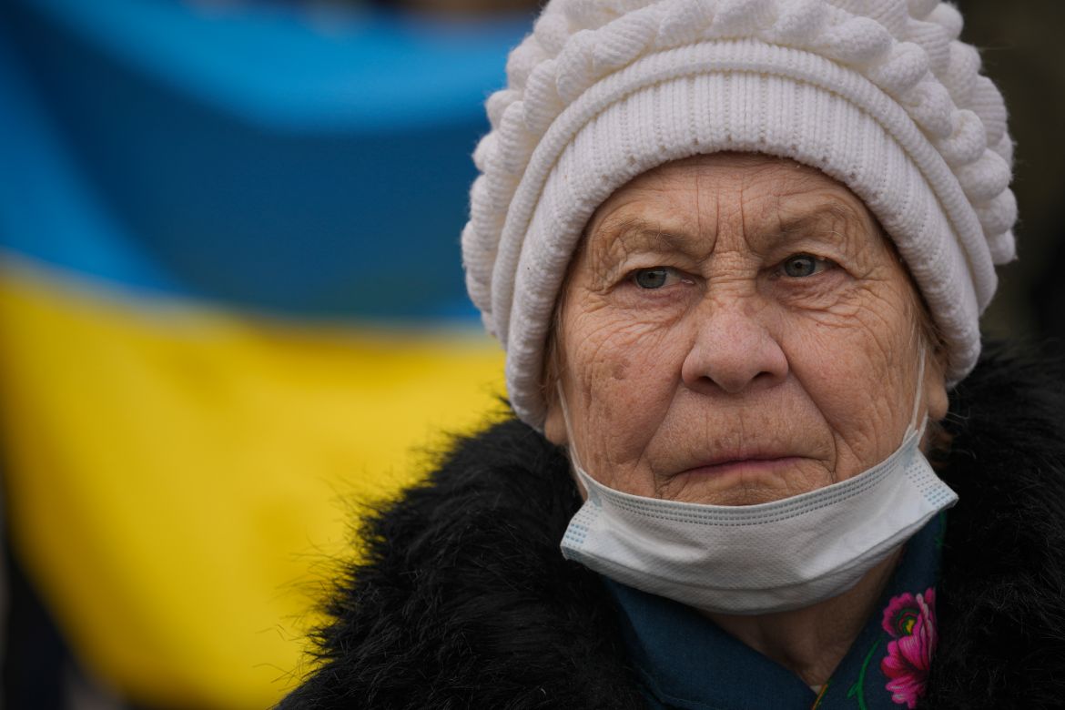 An elderly lady looks at people carrying a large Ukrainian flag as they mark a "day of unity" in Sievierodonetsk, the Luhansk region