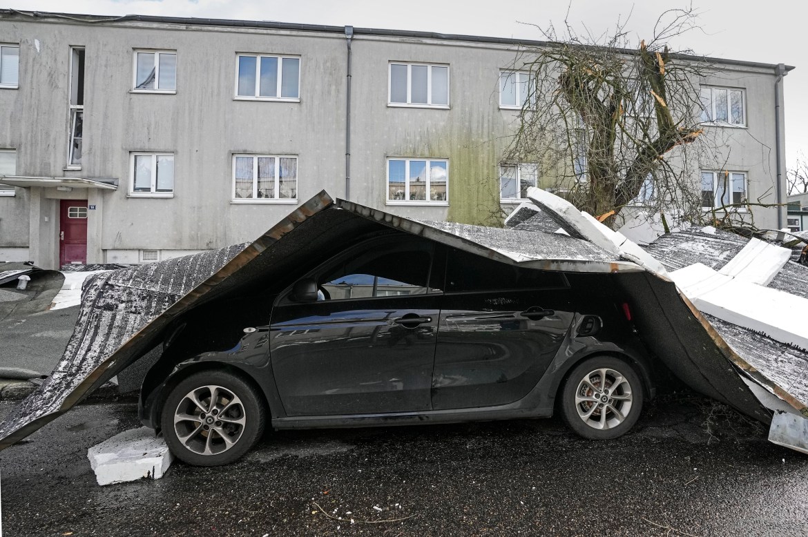 The roof of an apartment building is blown onto a car during a storm in Gelsenkirchen, Germany