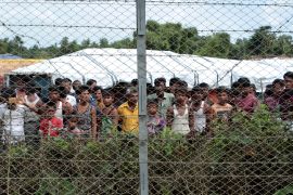 Rohingya men refugees are seen behind a fence