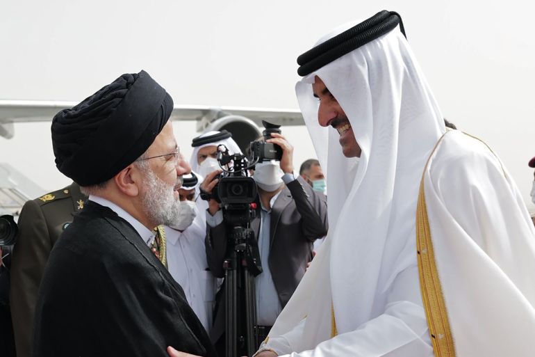 In this photo made available by Qatar News Agency, QNA, President Ebrahim Raisi, left, is welcomed by Qatari Emir Tamim bin Hamad Al Thani,