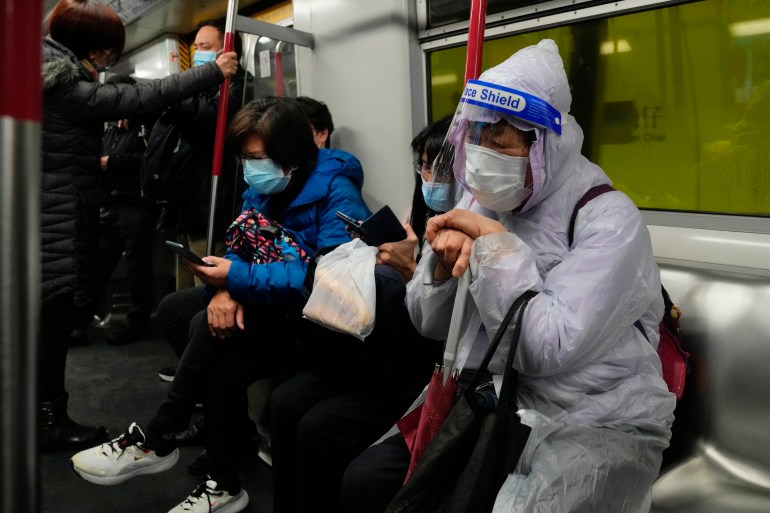 A passenger in full PPE sits on a Hong Kong MTR train