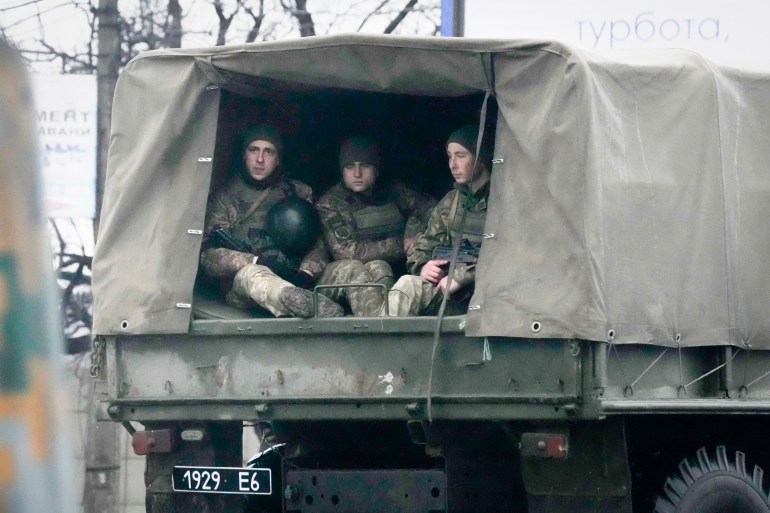 Ukrainian soldiers ride in a military vehicle in Mariupol, Ukraine