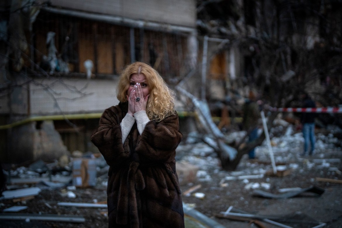 Natali Sevriukova reacts as she stands next to her house following a rocket attack in the city of Kyiv