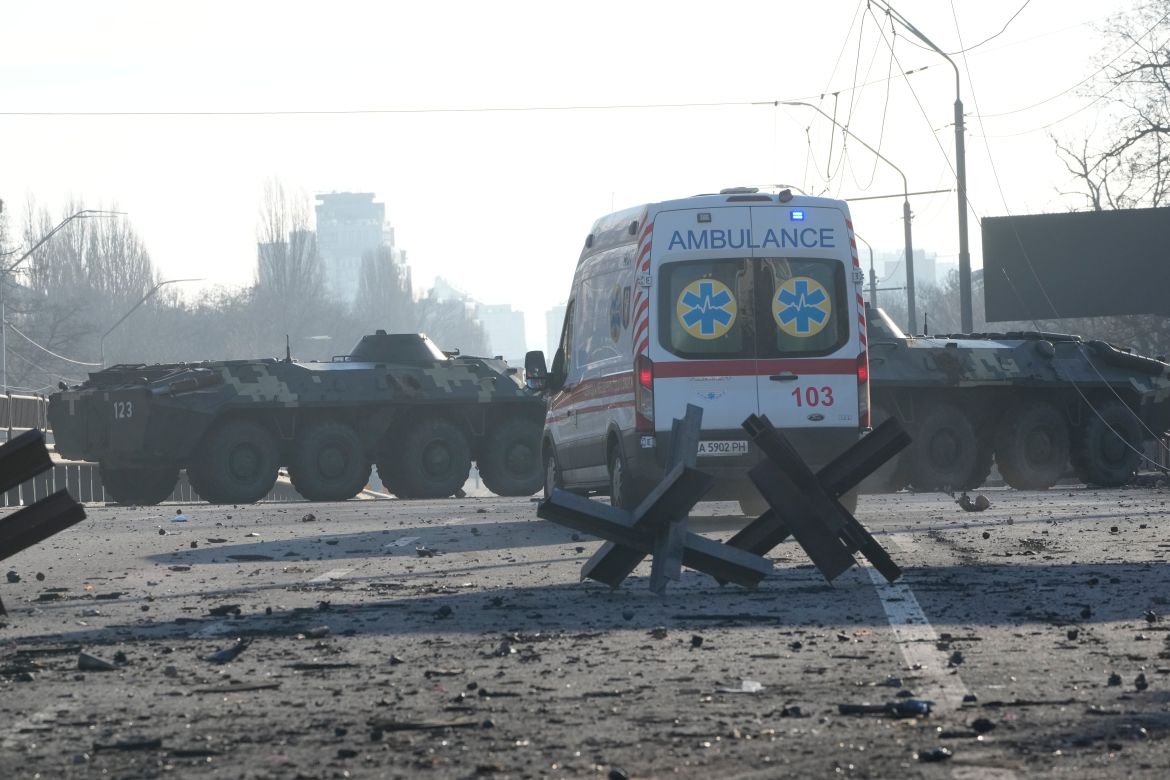 An ambulance parked near a barricade and Ukrainian armored vehicles in a street in Kyiv