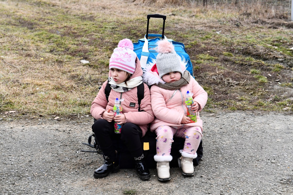 Two young girls are seen waiting at a checkpoint in Hungary