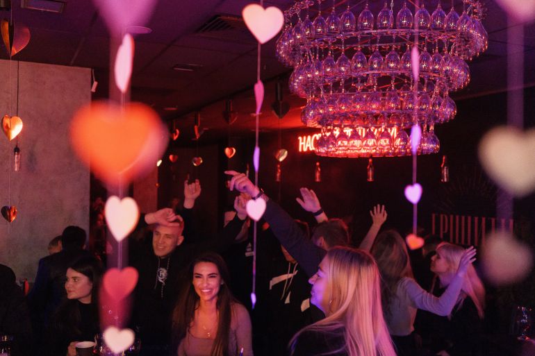 Ukrainians in the city of Mariupol dancing beneath a chandelier in nightclub tinged with red lighting