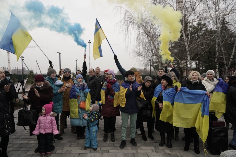 Women and men hold Ukrainian flags as they gather to celebrate a Day of Unity