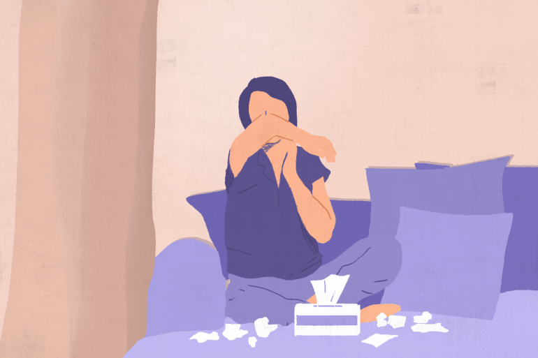 An illustration of a person coughing into their elbow whilst sat on a sofa with a tissue box and several used tissues on the table in front of them.