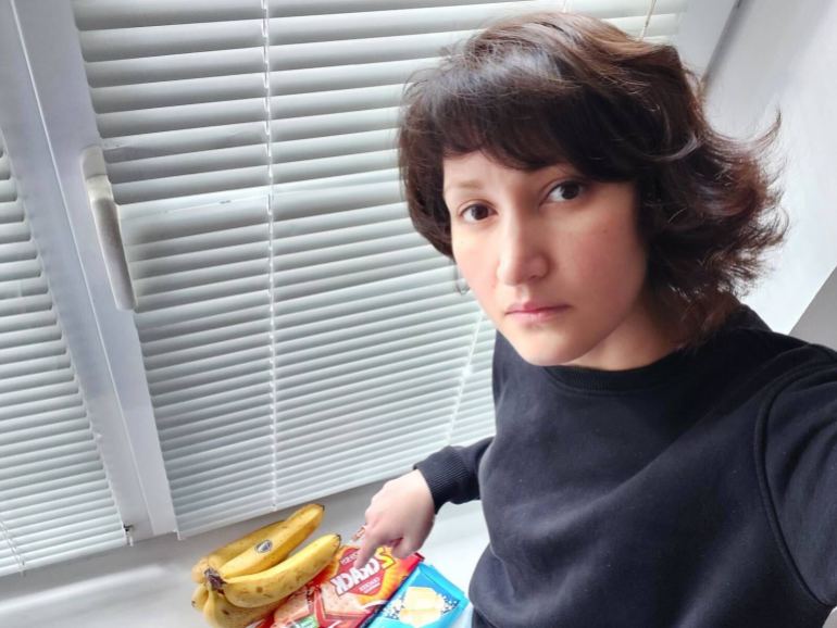 Zakhida Adylova, a Ukrainian woman with short, dark hair, shows Friday's purchase - a kilo of bananas, 2 chocolate bars and a packet of crackers