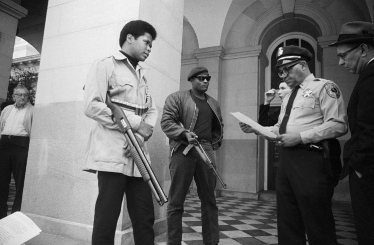 Two members of the Black Panther Party and a policeman on the steps of the State Capitol in Sacramento in 1967