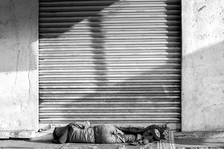 Black and white photo of a person sleeping on the street