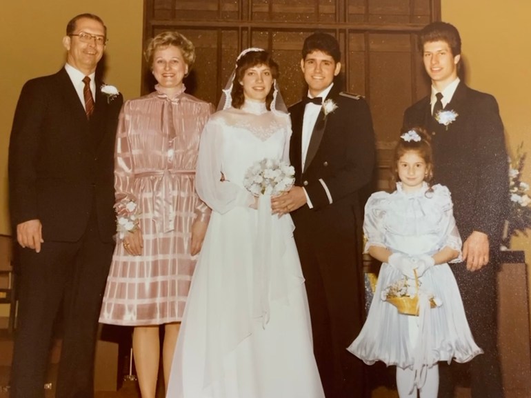 A wedding photo with the bride and groom in the middle, a man and woman on the left and a man and a child on the right.