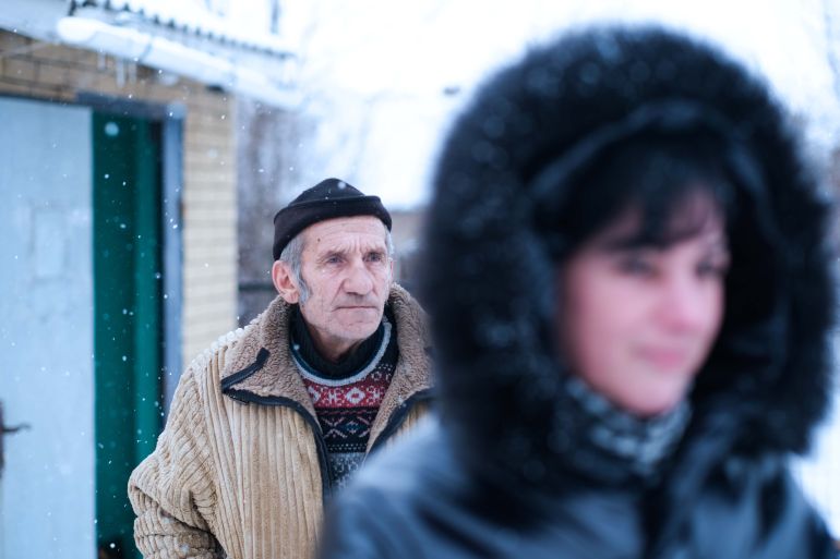 An elderly man and a young woman in front of him walk in the Ukrainian city of Popasna in the Luhansk region