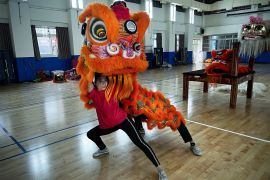 University student Qiu Zifang, 18, performs a southern style dance as the lion's head holding a red and orange lion mask over her own head